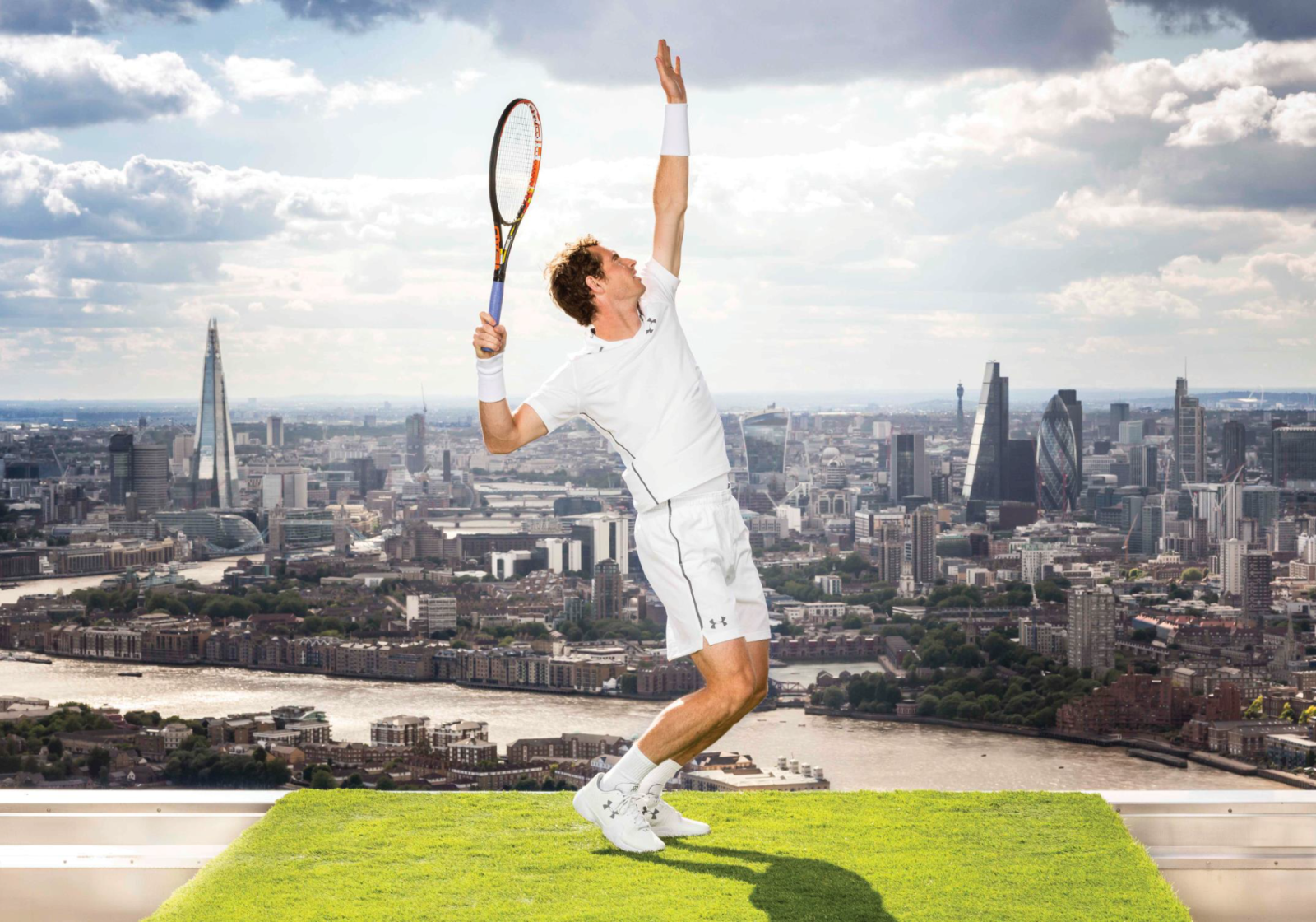 A male tennis player in a white outfit prepares to serve on a bright green grass court, positioned dramatically against a panoramic urban skyline. The Shard and other skyscrapers rise in the background, while fluffy clouds scatter across the sky.