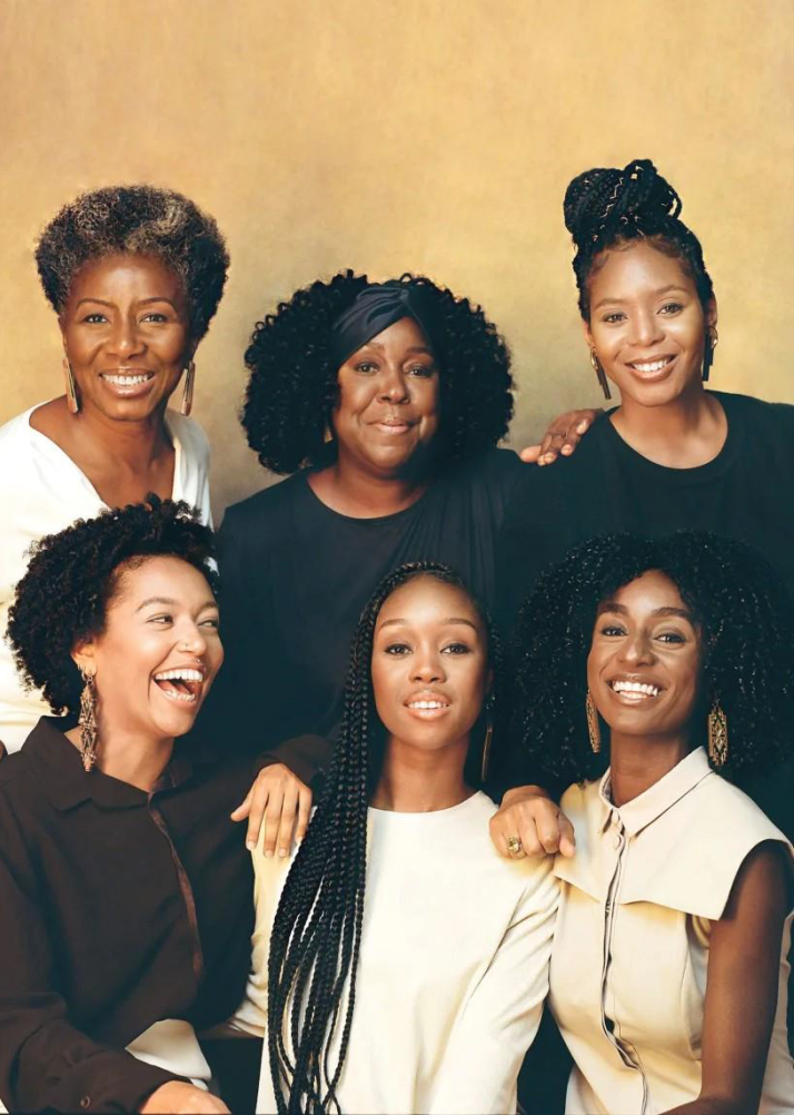 A stunning group portrait of six women, each displaying unique hairstyles and styles. They are arranged in two rows against a soft golden backdrop. The women exude elegance, with rich textures in their clothing enhancing their radiant presence in this beautifully composed photograph.