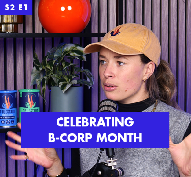 A woman with long brown hair, wearing a beige cap and grey sweater, gestures animatedly while speaking into a microphone. She is set against a backdrop of wooden panels and vibrant plants, with brightly coloured mugs and decor that add a lively touch to the scene.