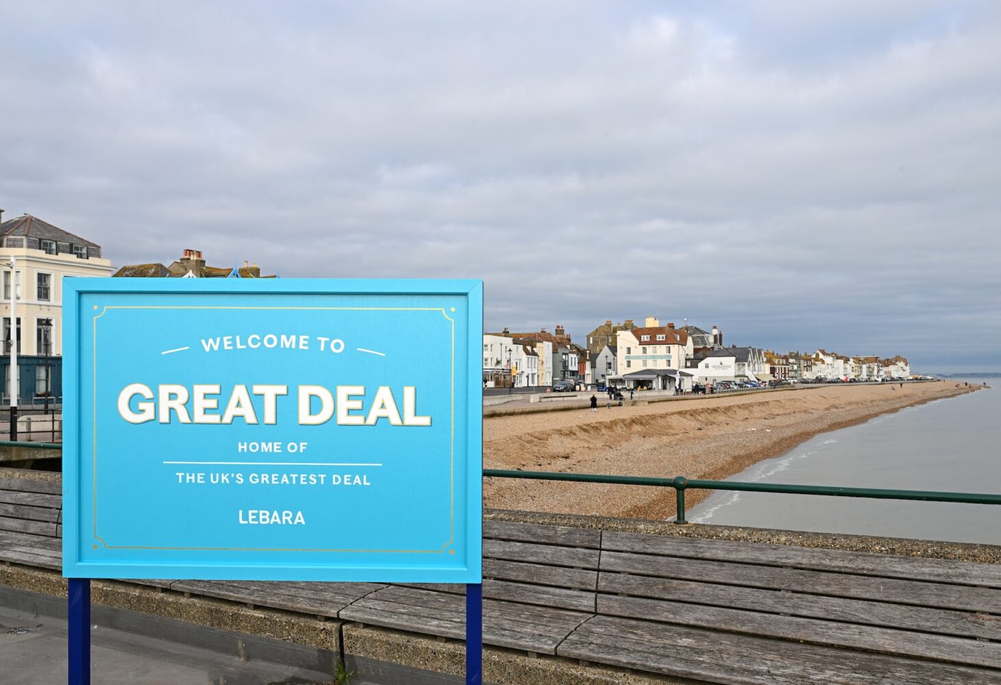 A seaside town with blue board in front of it saying Welcome to Great Deal