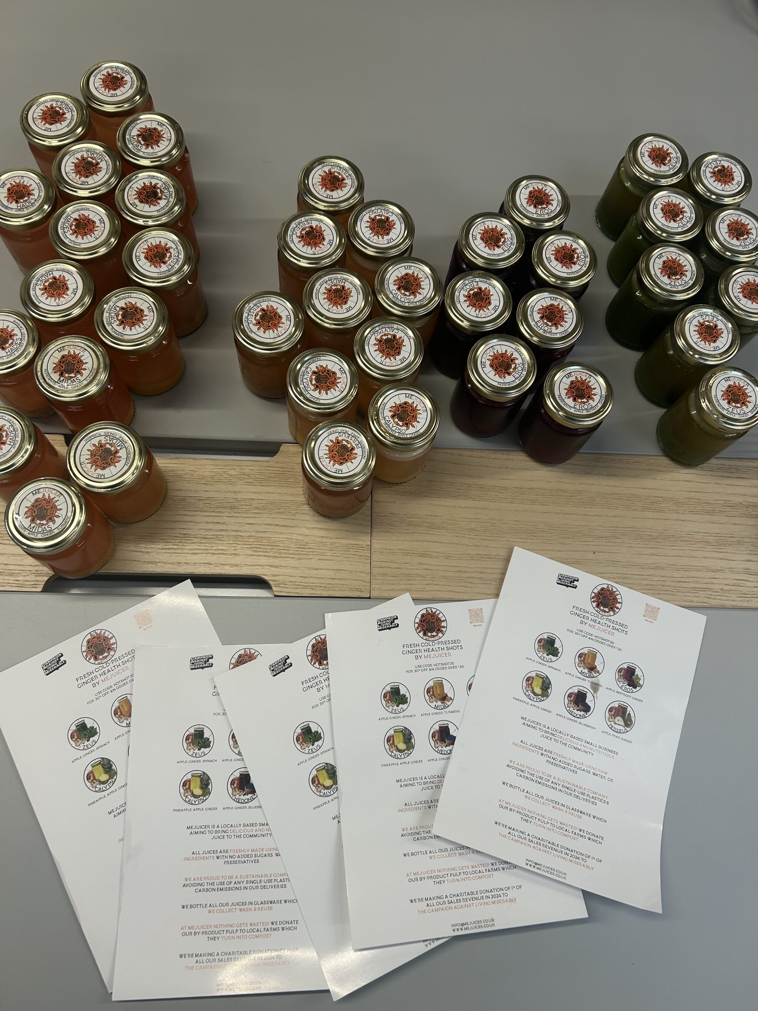 A selection of jars of juice on a table with information sheets in front