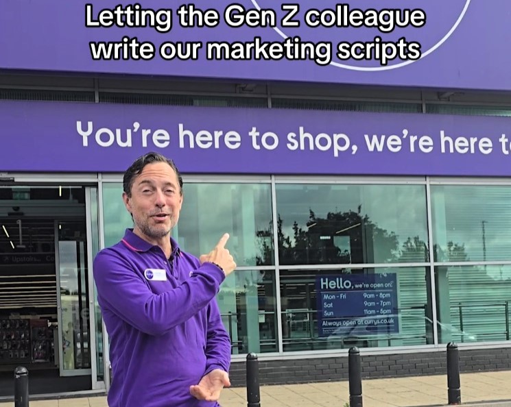 A man in a purple shirt stands in front of a store, pointing at a sign behind him. The sign reads, “You're here to shop, we're here to,” with incomplete text. The caption says, “Letting the Gen Z colleague write our marketing scripts.”.