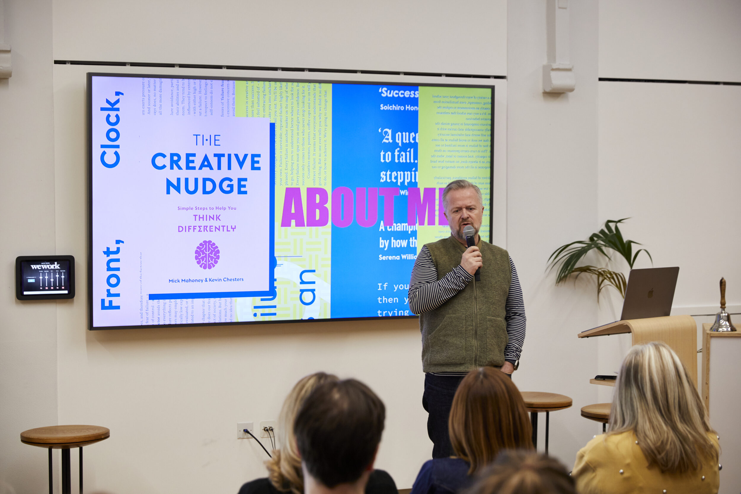 A man is delivering a presentation at the front of a room